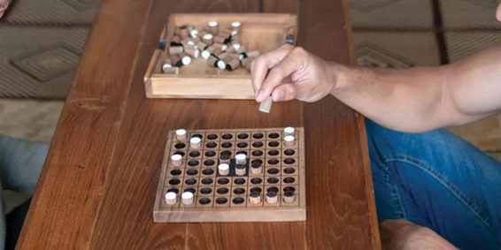 persoon speelt houten bordspel met pinnetjes op tafel